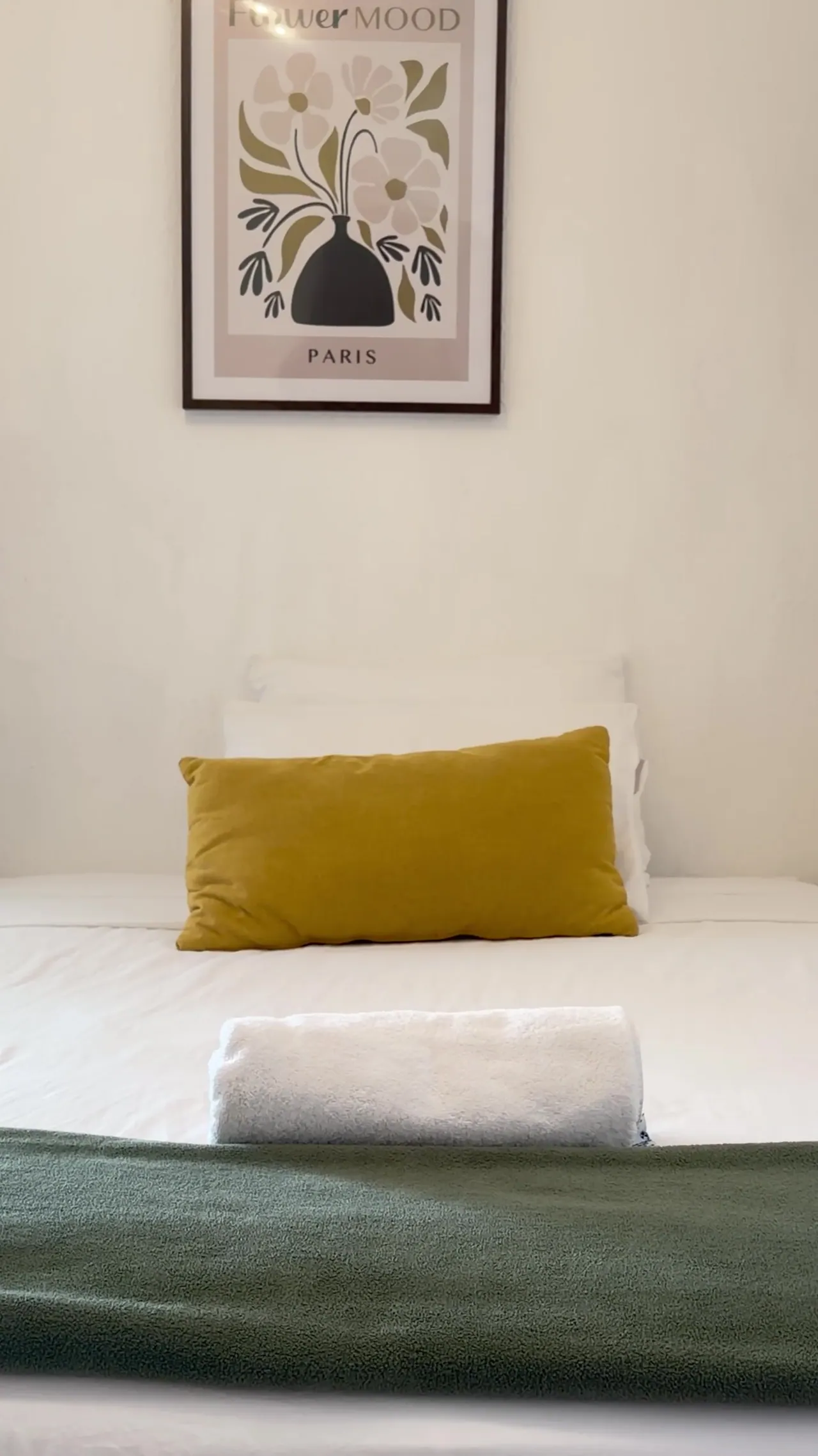 Cama con cuadro decorativo y cojín mostaza